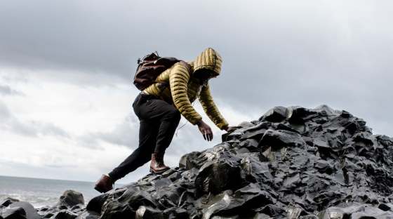 Hiker in jacket climbing over rocks